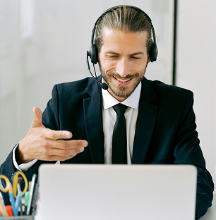 Professional in suit and tie with headset, smiling while working on laptop