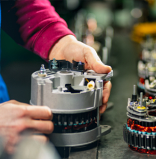 Close-up of technician's hands in pink workwear performing inspection or assembly of turbocharger core, with additional assemblies visible in background